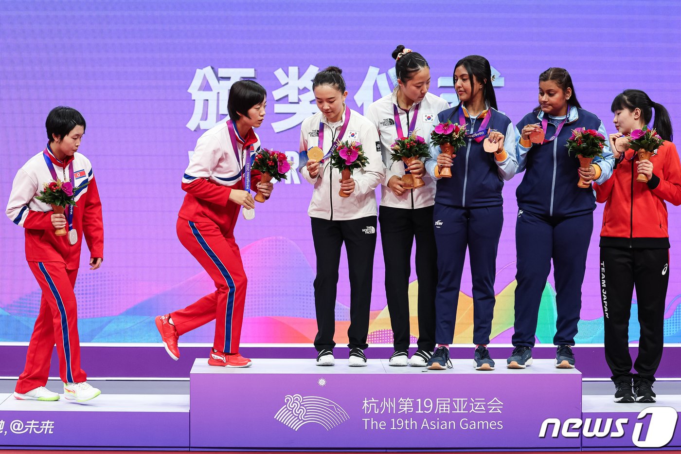 본문 이미지 - 2일 중국 항저우 궁수 캐널 스포츠파크 체육관에서 열린 2022 항저우 아시안게임 탁구 여자 복식 시상식에서 메달리스트들의 단체 기념 촬영 때 북한 차수영-박수경이 신유빈-전지희가 올라와 있는 시상대에 함께 오르고 있다. 2023.10.2/뉴스1 ⓒ News1 유승관 기자