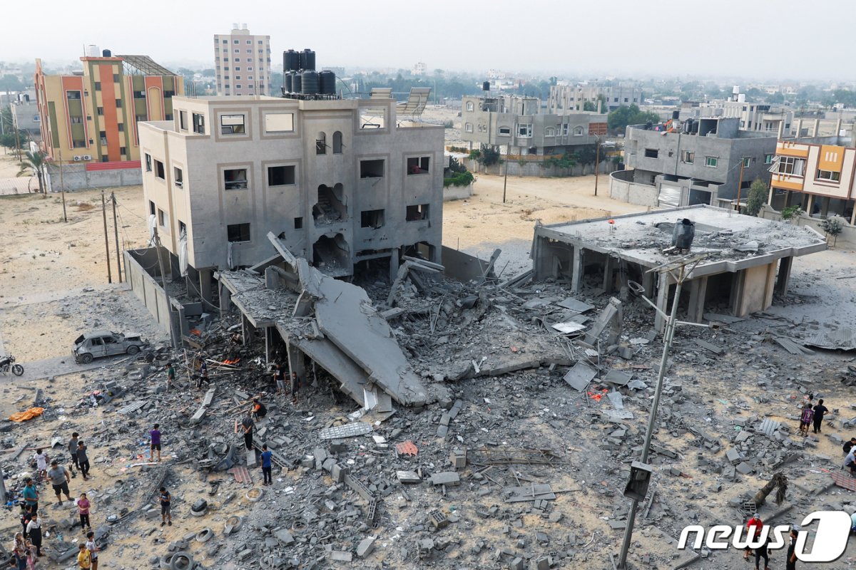 23일(현지시간) 팔레스타인 가자 지구 서부 칸 유니스 지역에서 이스라엘의 폭격으로 인해 무너진 건물 주변에 사람들이 모여있다. 2023.10.23 © 로이터=뉴스1 © News1 정지윤 기자