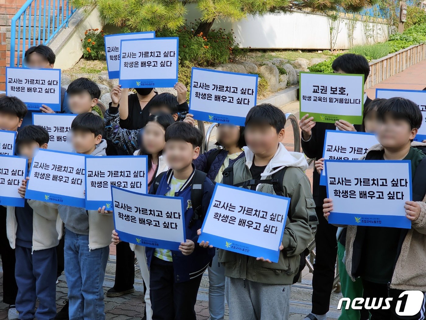 24일 광주 북구 한 초등학교 앞에서 열린 A교사 교권회복 촉구 집회에서 하교 하던 초등학생들이 피켓을 들고 집회에 참여하고 있다. A 교사는 학생 간 싸움을 말리는 과정에서 책상을 밀쳤다가 아동학대 혐의로 학부모에게 고소당해 검찰에서 무혐의 처분을 받았다. 학교 측은 이날 A 교사에 대한 교권보호위원회를 열었다. 2023.10.24./뉴스1 ⓒ News1 서충섭 기자