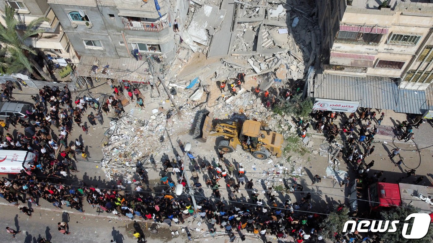 본문 이미지 - 24일(현지시간) 팔레스타인 무장 정파 하마스에 대응한 이스라엘 군의 포격을 받은 가자 지구 칸 유니스의 폭삭 무너진 주택서 주민들이 수색하는 모습을 지켜 보고 있다. 2023.10.25 ⓒ 로이터=뉴스1 ⓒ News1 우동명 기자