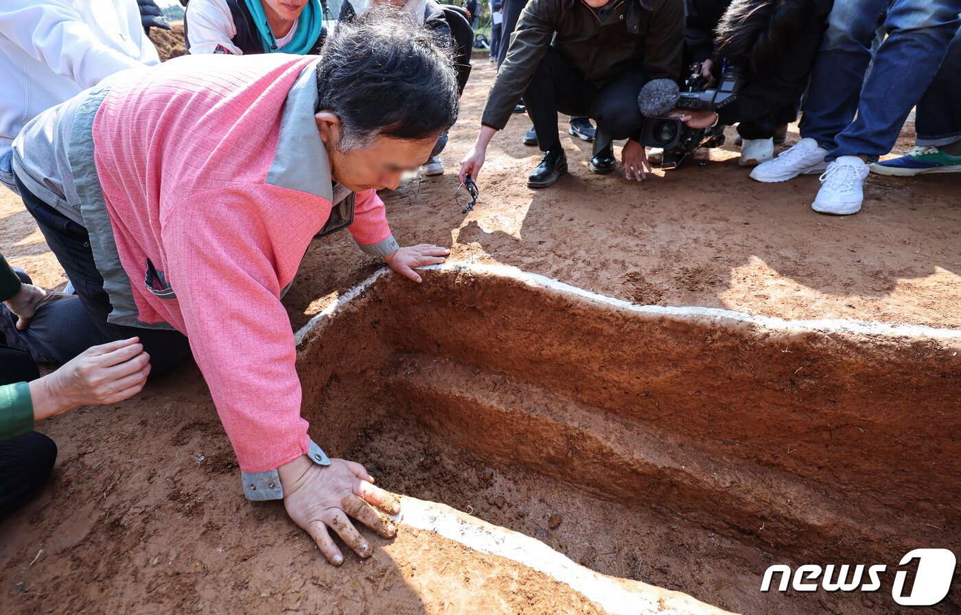 본문 이미지 - 25일 경기도 안산시 단원구 선감도에서 진실화해위원회 주최한 선감학원 아동 인권침해 사건 유해발굴 현장 언론공개 설명회에서 희생자의 친구가 발굴현장을 만져보고 있다.  2023.10.25/뉴스1 ⓒ News1 김도우 기자