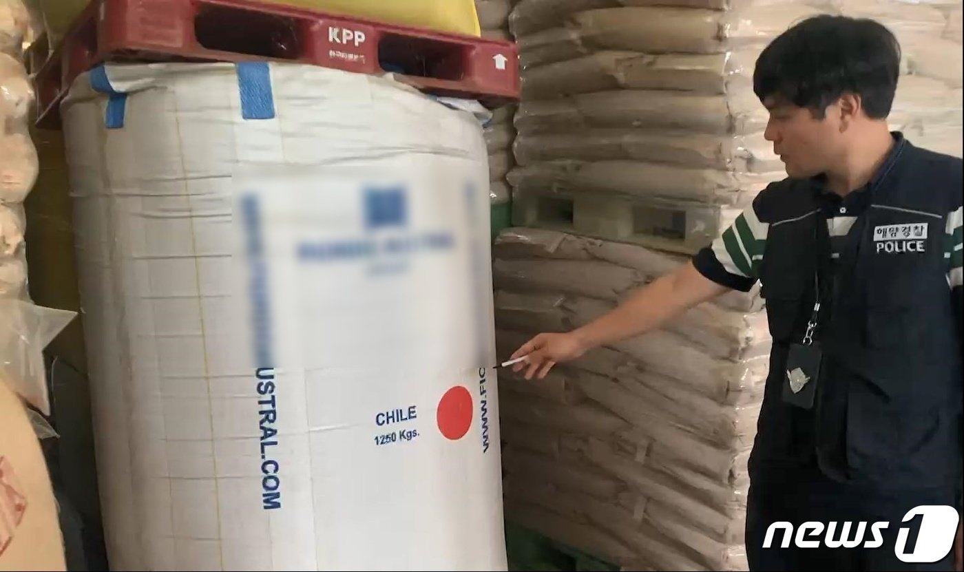 본문 이미지 - 서귀포해경이 C제조업체에서 칠레산으로 포대갈이 된 사료를 확인하고 있다.(서귀포해양경찰서 제공)