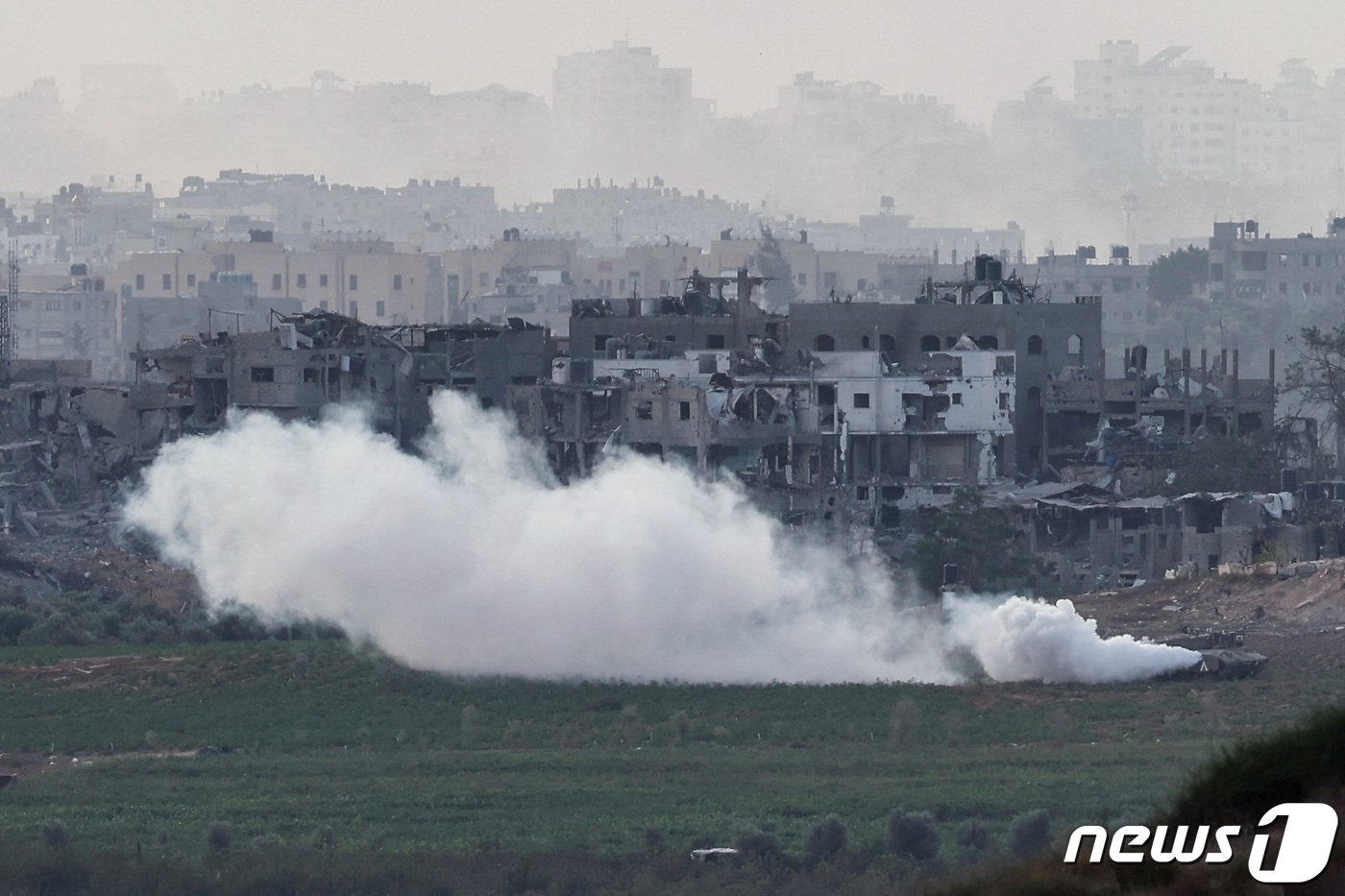 본문 이미지 - 폐허가 된 마을을 배경으로 이스라엘 탱크가 연기를 내뿜으며 29일(현지시간) 가자 지구로 진입하고 있다. 2023.10.30 ⓒ 로이터=뉴스1 ⓒ News1 정지윤 기자