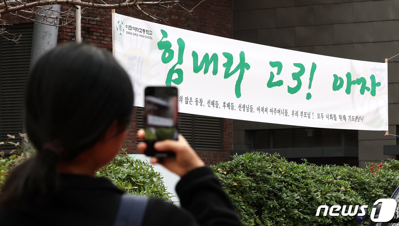 본문 이미지 - 2024학년도 대학수학능력시험 예비소집일인 15일 서울 중구 이화여고에서 한 수험생이 시험장 앞에 붙은 응원 현수막을 스마트폰에 담고 있다. 2023.11.15/뉴스1 ⓒ News1 박지혜 기자