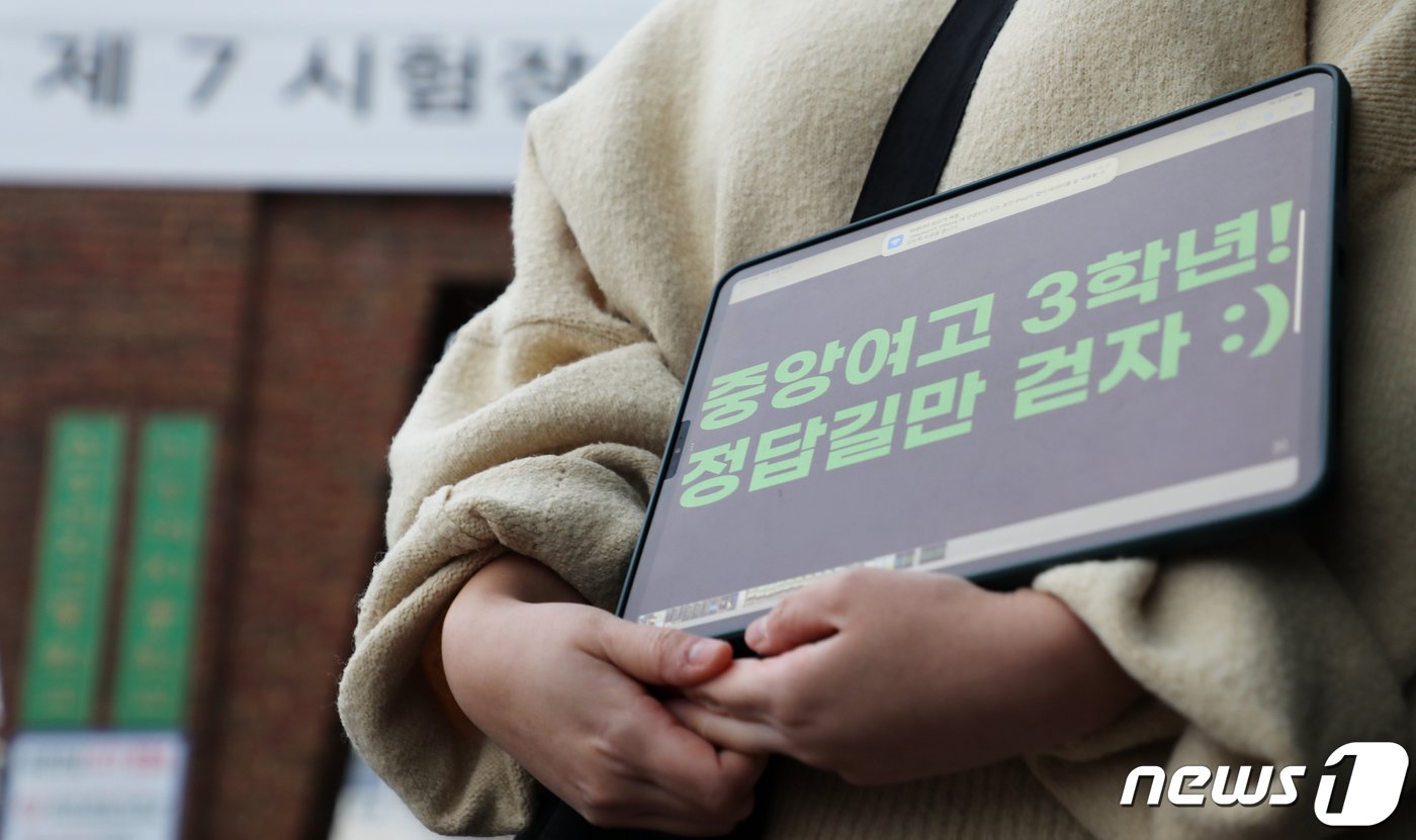 본문 이미지 - 2024학년도 대학수학능력시험일인 16일 오전 제주도교육청 95지구 제7시험장 신성여자고등학교 앞에서 제주중앙여자고등학교 교사 현재연씨가 '중앙여고 3학년! 정답길만 걷자 :)'라는 문구를 띄운 태블릿을 두 손으로 들고 제자들을 응원하고 있다.2023.11.16./뉴스1 ⓒ News1 오미란 기자