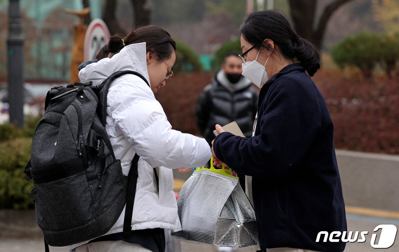 본문 이미지 - 2024학년도 대학수학능력시험일인 16일 오전 서울 양천구 금옥여자고등학교 앞에서 어머니가 수험생에게 도시락을 건네고 있다. 2023.11.16/뉴스1 ⓒ News1 장수영 기자