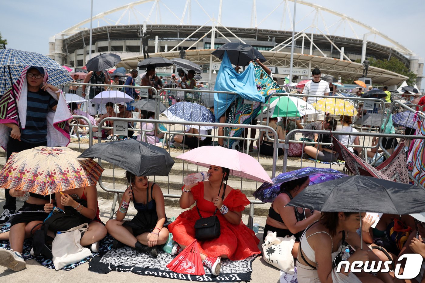 본문 이미지 - 지난 11월 18일 브라질 리우데자네이루 닐톤 산토스 스타디움 앞에 미국 팝스타 테일러 스위프트의 공연을 보려는 현지 팬들이 폭염에 우산을 펼치고 입장을 기다리고 있다. 2023.11.18. ⓒ 로이터=뉴스1 ⓒ News1 김성식 기자