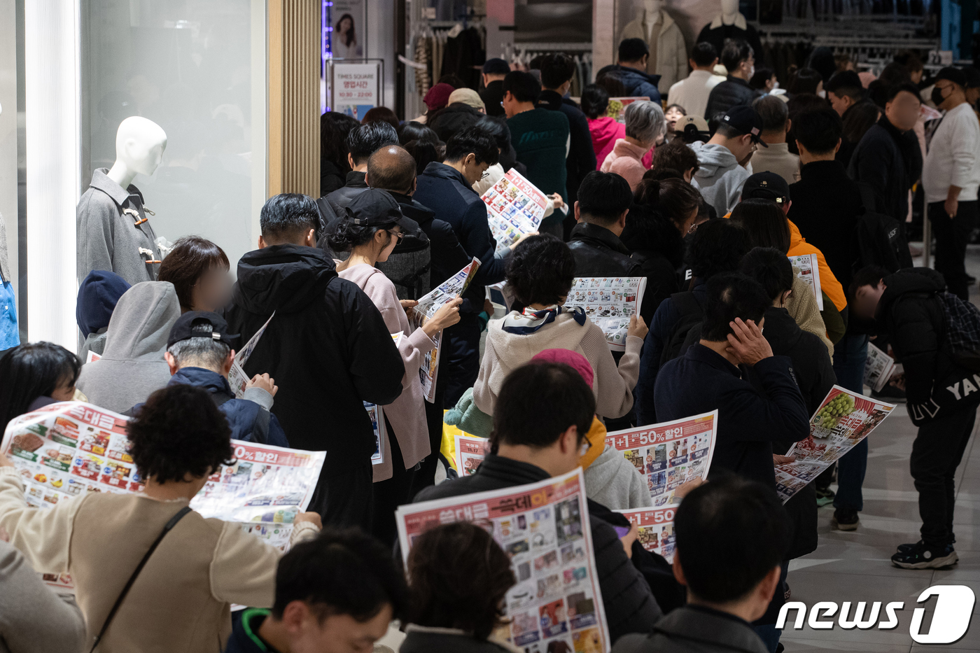 (서울=뉴스1) 유승관 기자 = 19일 서울 이마트 영등포점을 찾은 고객들이 매장 개장 시간 전에 입장을 위해 길게 줄지어 서서 행사 전단을 살펴보고 있다.이마트는 신세계 그룹 통 …