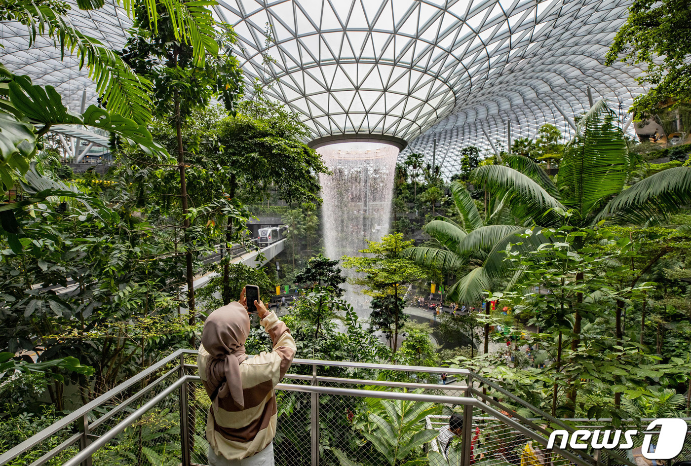 (싱가포르=뉴스1) 공항사진기자단 = 23일 오전(현지시간) 싱가포르 창이국제공항 쥬얼창이를 찾은 관광객들이 인공폭포를 관람하고 있다.쥬얼창이는 기존 창이공항 시설 확장 및 허브 …