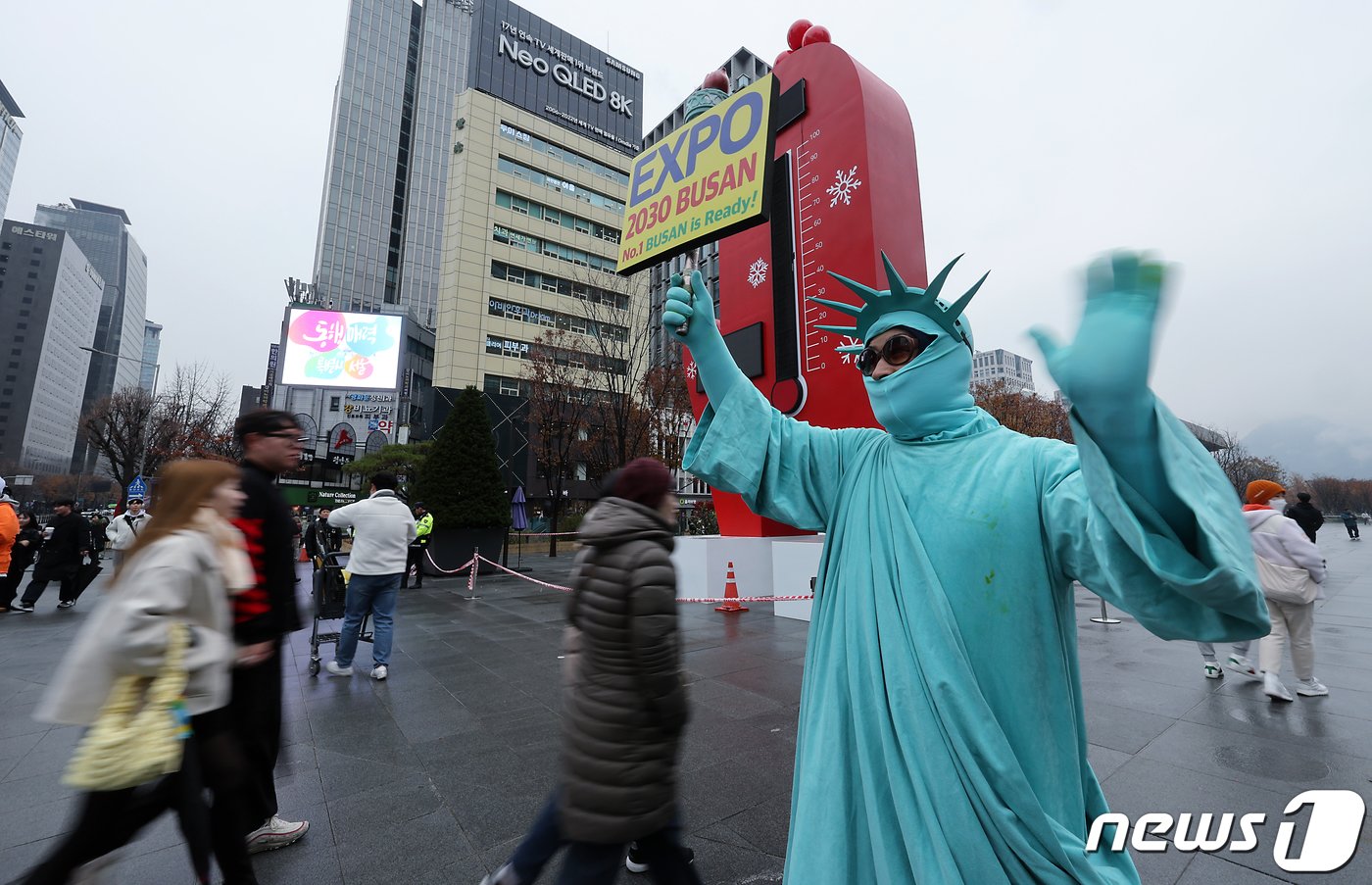 2030 세계박람회&#40;엑스포&#41; 개최지 발표를 하루 앞둔 27일 오후 서울 종로구 광화문광장에서 자유의 여신상 옷을 입은 한 시민이 부산엑스포 유치를 염원하는 &#39;EXPO 2023 BUSAN, No1 BUSAN is Ready!&#39;가 적힌 손피켓을 들고 지나는 시민들에게 인사하고 있다. 부산 옆 거제가 고향이라고 밝힌 이 시민은 &#34;너무 간절해서 나왔다＂고 밝혔다. 2023.11.27/뉴스1 ⓒ News1 박정호 기자