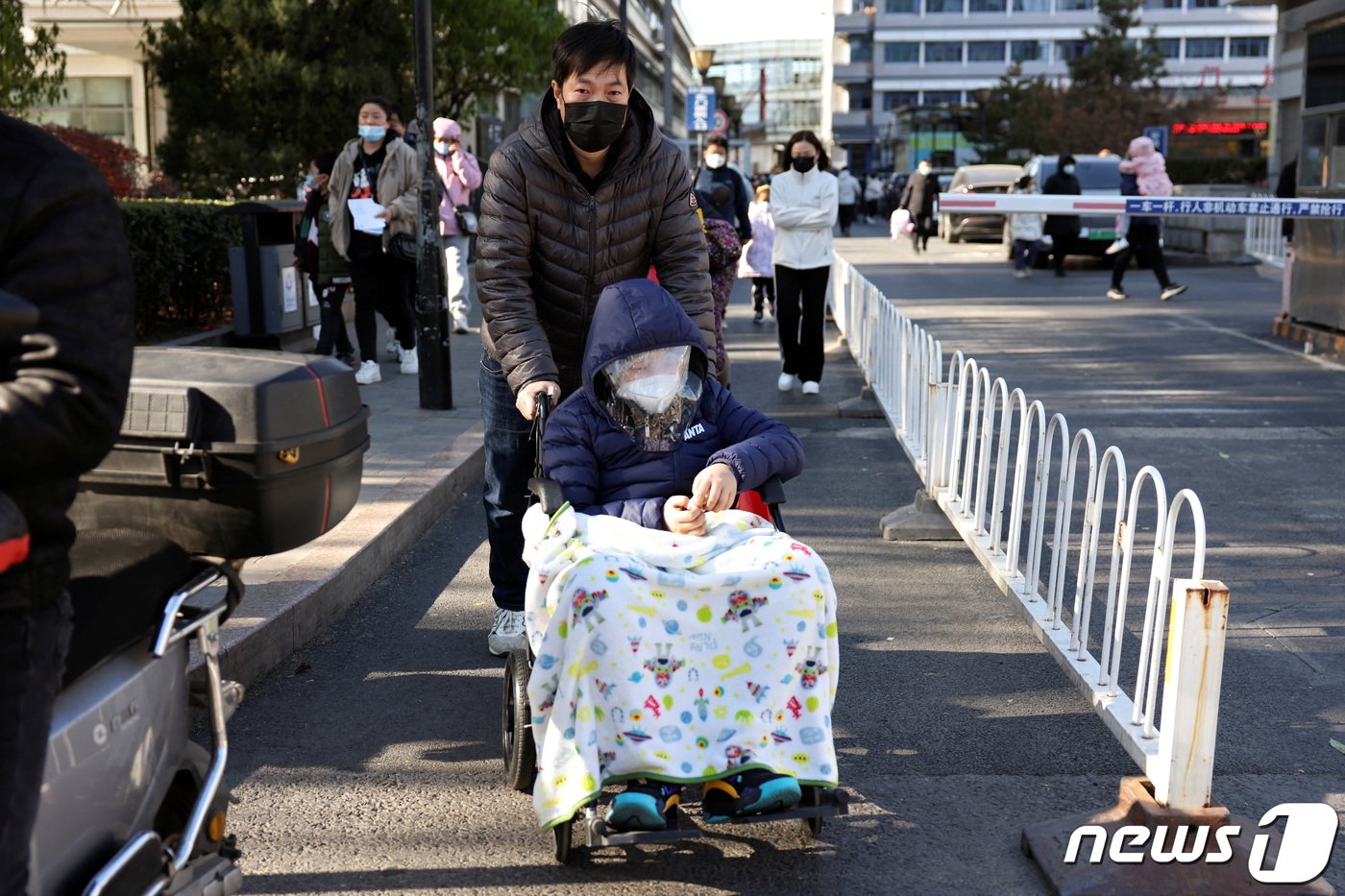 한 아버지가 아이를 휠체어에 태워 아동병원으로 가고 있다. ⓒ 로이터=뉴스1 ⓒ News1 박형기 기자