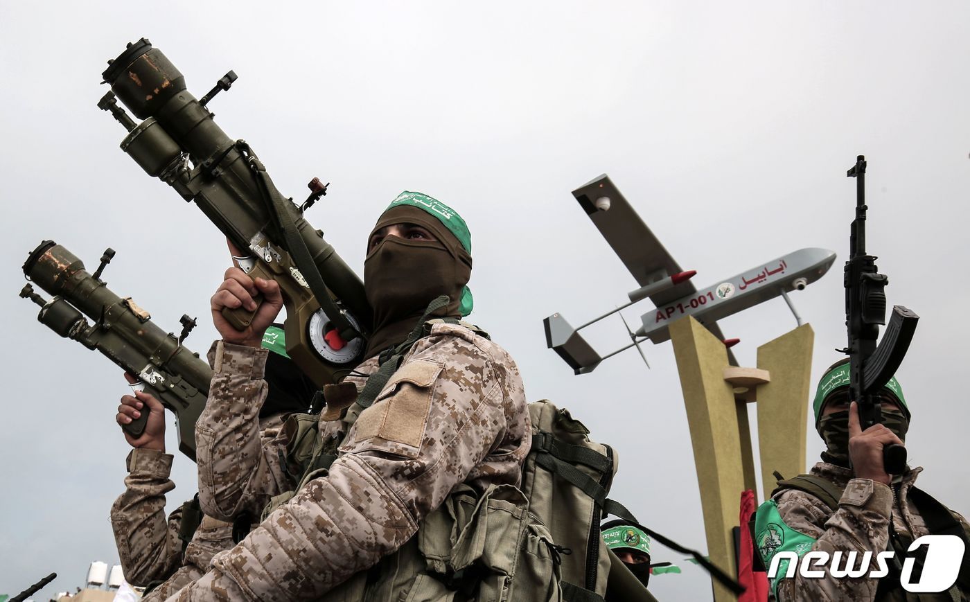 본문 이미지 - 팔레스타인 무장정파 하마스 소속 알카삼 여단 전투원들이 2017년 1월 가자지구 라파에서 열린 튀니지 출신 항공우주 연구원 모하메드 주아리(49) 추모식에 참석한 모습. 무기를 든 대원들 뒤로 주아리가 생전에 개발한 자폭드론 '주아리'(Zouari)가 보인다. 2017.1.31. ⓒ AFP=뉴스1 ⓒ News1 김성식 기자