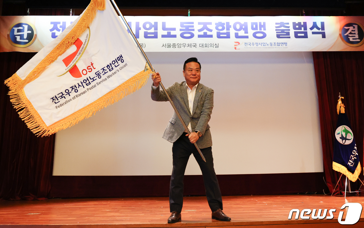 (서울=뉴스1) 허경 기자 = 이동호 우정노조 위원장이 30일 서울 중구 중앙우체국에서 열린 전국우정사업노동조합연맹 출범식에서 연맹기를 흔들고 있다. 2023.11.30/뉴스1