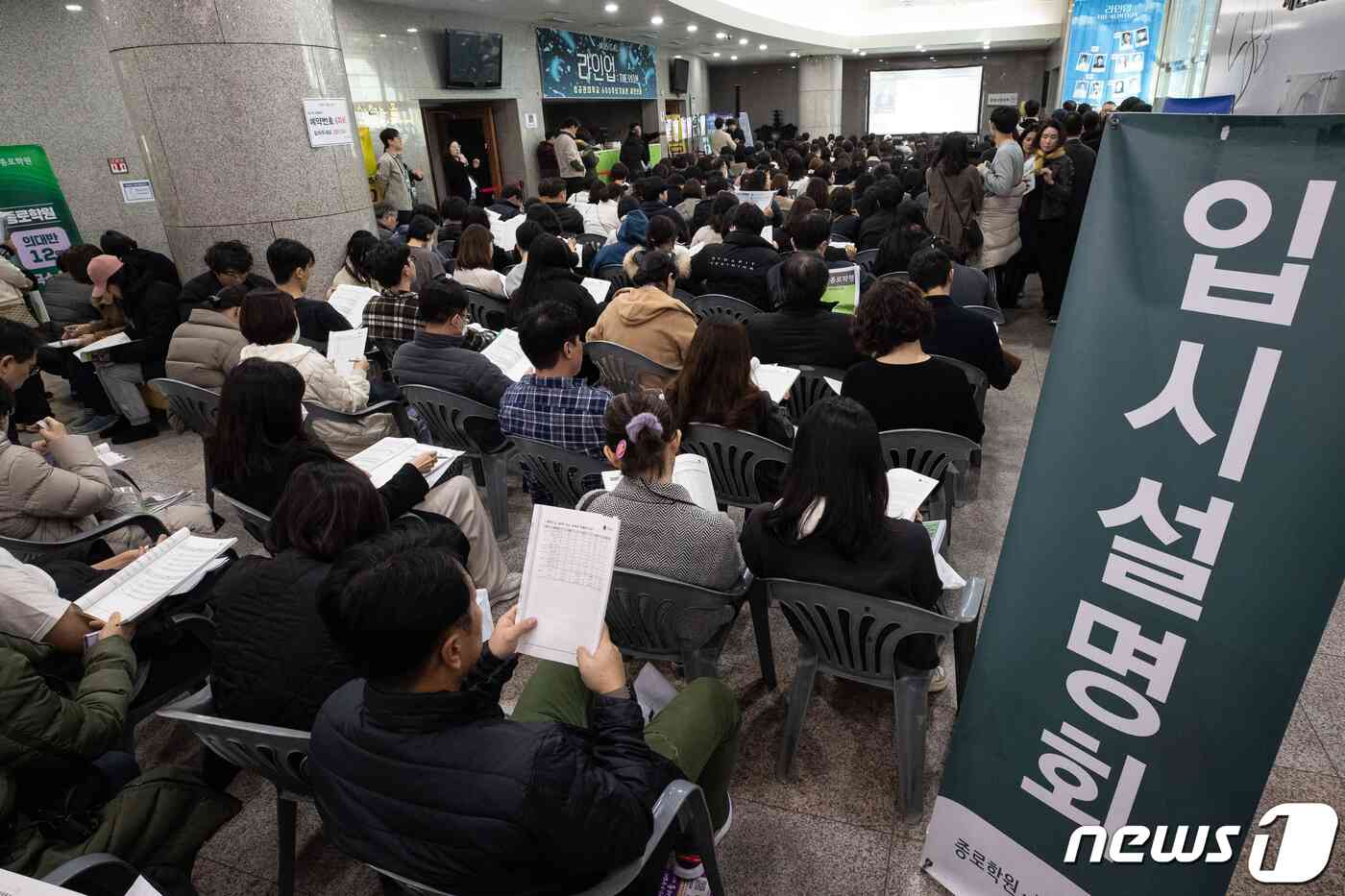 수험생 및 학부모들이 10일 서울 종로구 성균관대 600주년 기념관에서 열린 종로학원 '2024 정시지원 변화 및 합격선 예측, 합격전략' 설명회에서 설명회장 밖에 마련된 좌석에 앉아 정시배치참고표 및 자료집을 살펴보고 있다. 2023.12.10/뉴스1 © News1 유승관 기자