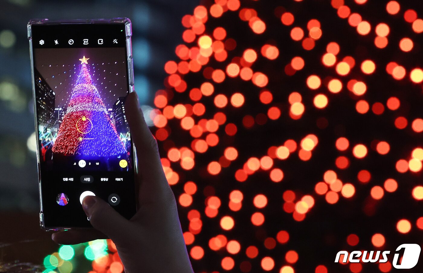 본문 이미지 - 15일 오후 서울 세종대로 광화문광장에서 열린 ‘2023 서울빛초롱축제’에서 한 시민이 미디어트리를 스마트폰으로 촬영하고 있다. 이번 행사는 이날 개막해 내년 1월 21일까지 38일간 진행된다. 2023.12.15/뉴스1 ⓒ News1 김진환 기자