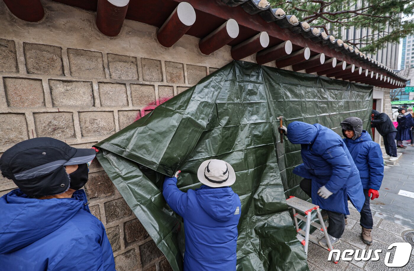 본문 이미지 - 경복궁 관리소 직원들이 2023년 12월 16일 오전 서울 종로구 경복궁 서쪽 담벼락에 낙서로 훼손된 부분을 천막으로 가리고 있다. 1 2023.12.16/뉴스1 ⓒ News1 김도우 기자