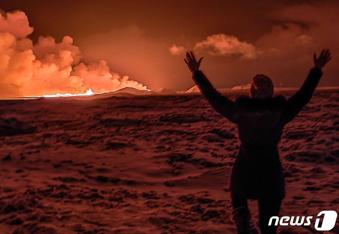 본문 이미지 - 18일(현지시간) 아이슬란드 남서부 레이캬비크반도에서 화산이 분화하며 화산재를 내뿜고 있는 가운데 지역 주민이 이 광경을 바라보며 두 손을 들고 있다. 2023.12.18 ⓒ AFP=뉴스1 ⓒ News1 정지윤 기자