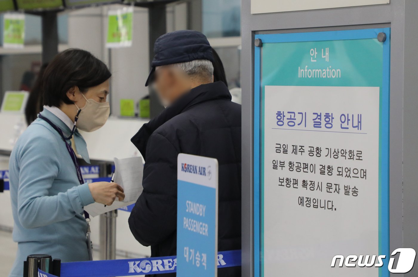 본문 이미지 - 이틀째 올겨울 최강 한파가 제주를 덮친 22일 오전 제주국제공항에서 항공사 관계자가 승객에게 예약 관련 사항을 안내하고 있다. 2023.12.22/뉴스1 ⓒ News1 오현지 기자