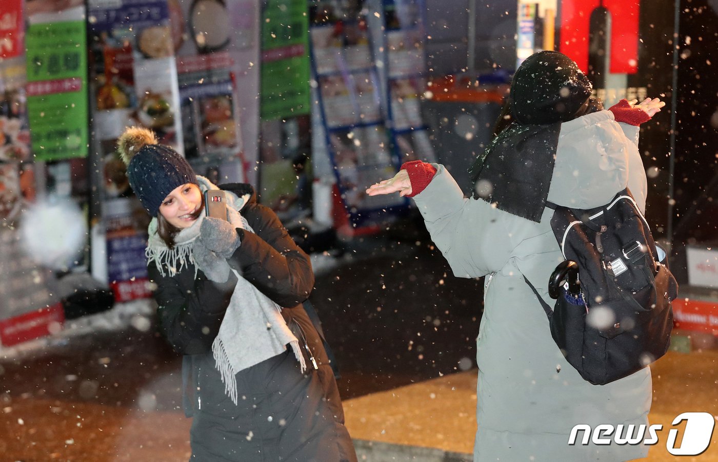 서울을 비롯한 중부지역에 눈이 내리고 있는 25일 새벽 서울 중구 명동거리에서 외국인 관광객이 눈을 맞으며 사진을 찍고 있다. 서울은 이번 눈으로 8년만에 화이트 크리스마스다. 2023.12.25/뉴스1 ⓒ News1 박세연 기자