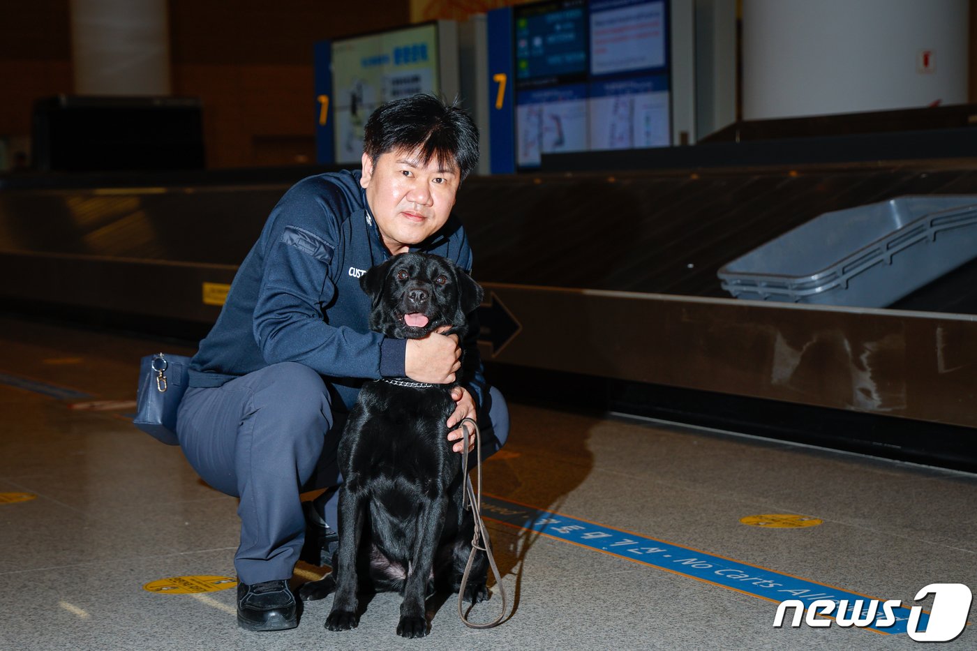 탐지견 에이스&#40;5·래브라도 리트리버&#41;가 탐지조사요원인 박지용 주무관&#40;50&#41;과 인천국제공항 제2터미널 입국장에서 여행객들의 수화물을 검색한 뒤 포즈를 취하고 있다. ⓒ News1 안은나 기자