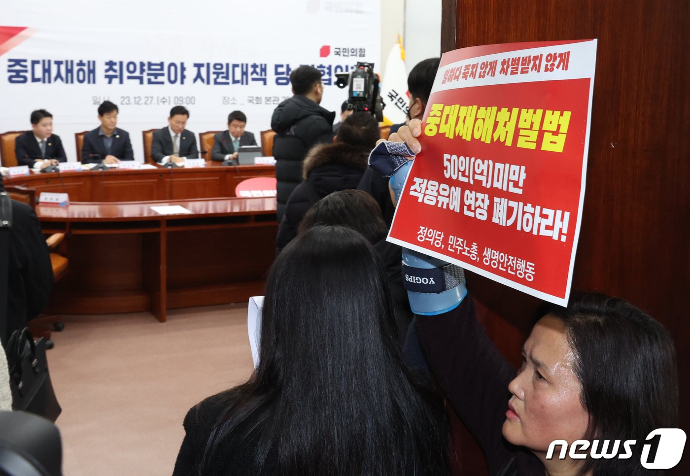 본문 이미지 - 고 김용균씨 어머니 김미숙씨가 27일 서울 여의도 국회에서 열린 중대재해 취약분야 지원대책 관련 당정협의회 회장 앞에서 '중대재해처벌법 적용유예연장 폐기' 손 피켓을 들고 있다. 2023.12.27/뉴스1 ⓒ News1 송원영 기자