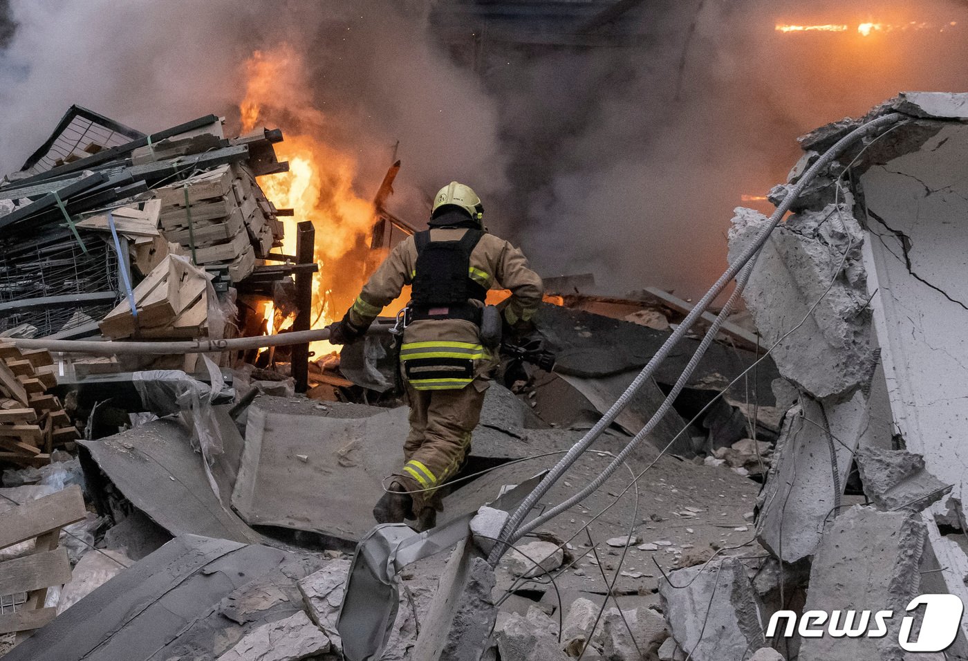 본문 이미지 - 29일&#40;현지시간&#41; 우크라이나 하르키우에서 소방관이 러시아의 공습으로 붕괴한 건물에서 발생한 화재를 진압하기 위해 호스를 들고 불길 속으로 뛰어들고 있다. 2023.12.29/ ⓒ 로이터=뉴스1 ⓒ News1 권진영 기자