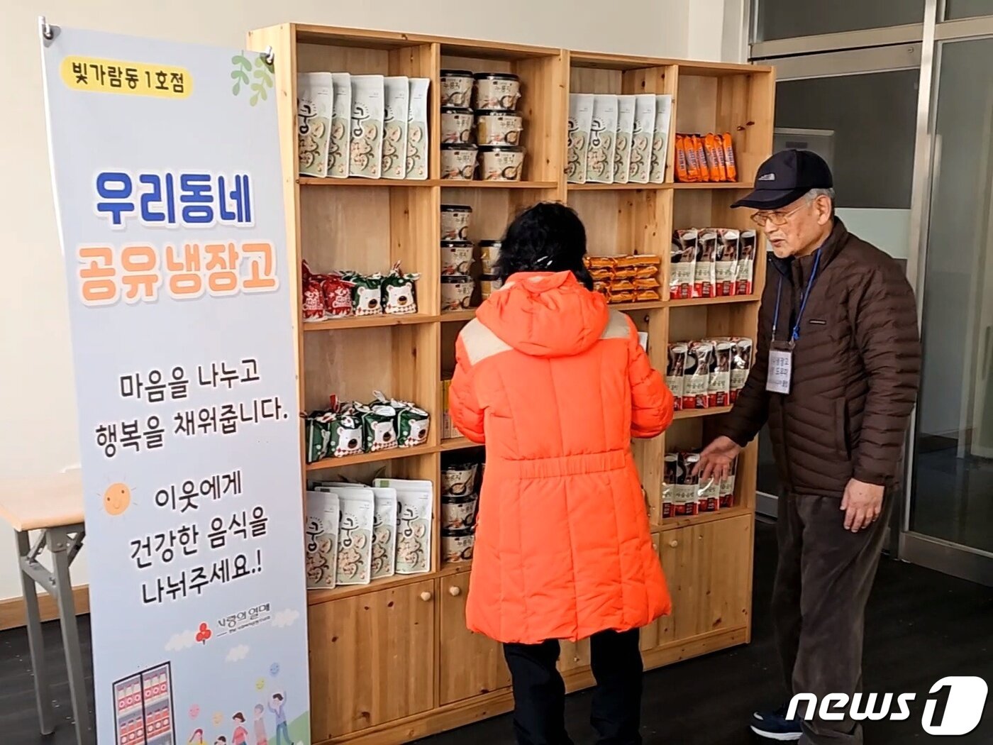 본문 이미지 - 나주혁신도시 빛가람동 LH5단지 아파트 주민카페에 설치된 공유냉장고를 이용하는 주민을 운영도우미 국경표씨(오른쪽)가 안내하고 있다.2023.12.27./뉴스1 ⓒ News1 서충섭 기자