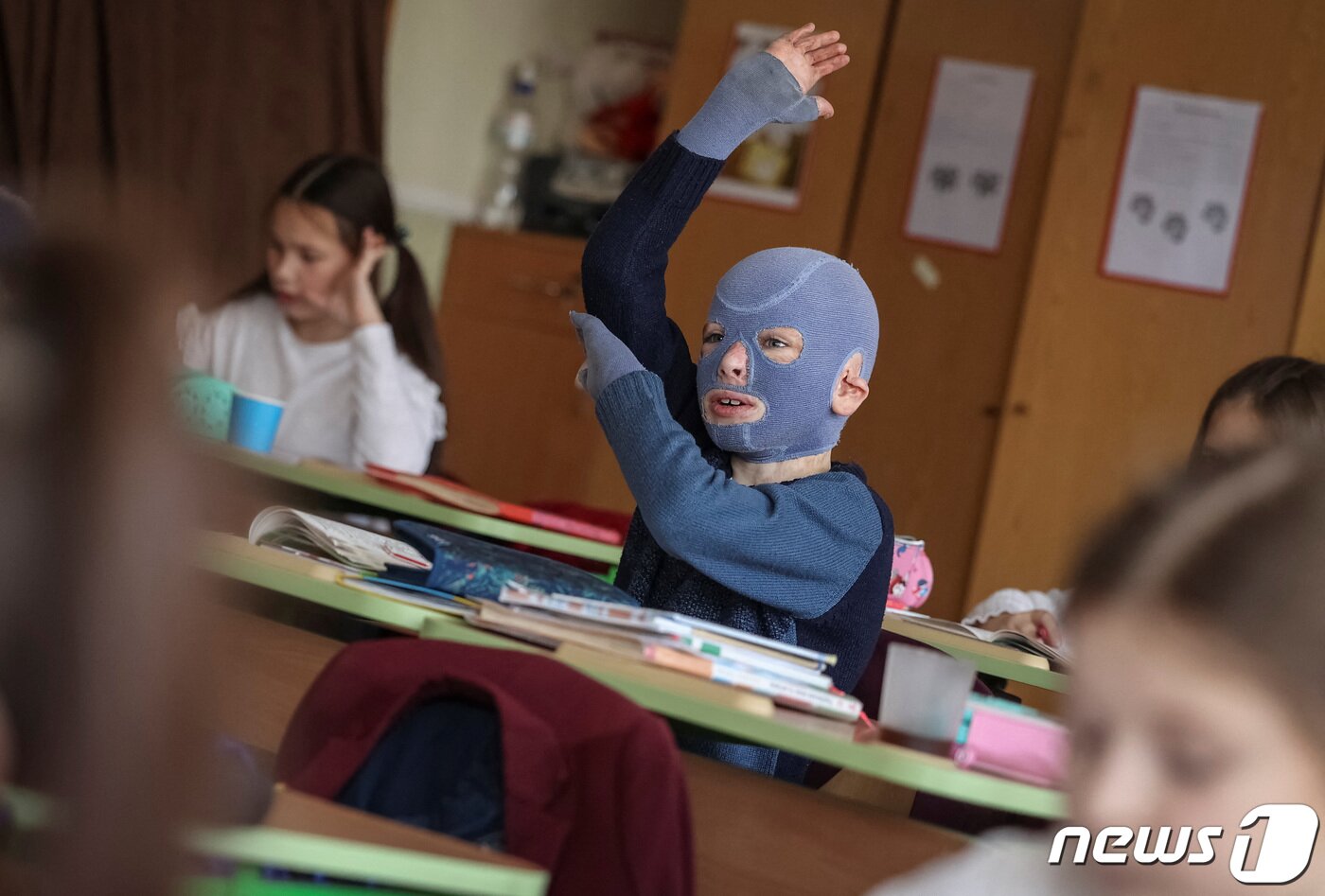 본문 이미지 - 4일(현지시간) 우크라이나 르비우의 한 학교에서 로만(8)이 손을 번쩍 들며 적극적으로 수업에 참여하고 있다. 그는 러시아의 공격으로 몸의 절반 가까이 화상을 입고 30여 차례의 수술을 받았다. 2023.12.04/ ⓒ 로이터=뉴스1 ⓒ News1 권진영 기자