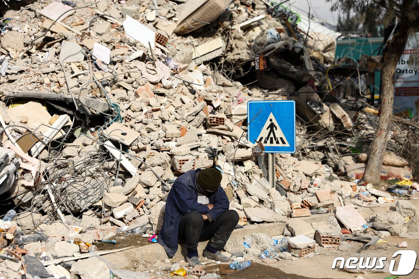 본문 이미지 - 규모 7.8의 강진이 발생한 지 닷새째인 10일(현지시간) 튀르키예 카라만라스에서 한 주민이 산더미처럼 쌓인 건물 잔해 앞에 앉아 망연자실한 듯 고개를 떨구고 있다. 2023.2.10. ⓒ 로이터=뉴스1 ⓒ News1 김성식 기자