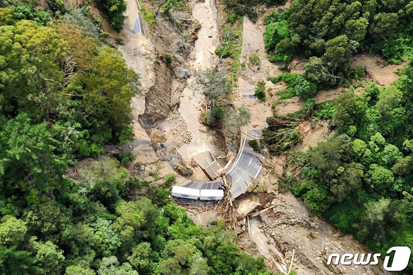 본문 이미지 - 14일 (현지시간) 사이클론 ‘가브리엘’이 휩쓸고 간 뉴질랜드 북섬 와이로아의 쓰레기로 덮인 도로에 갇힌 트럭이 보인다.  2023.02.14. ⓒ AFP=뉴스1 ⓒ News1 우동명 기자