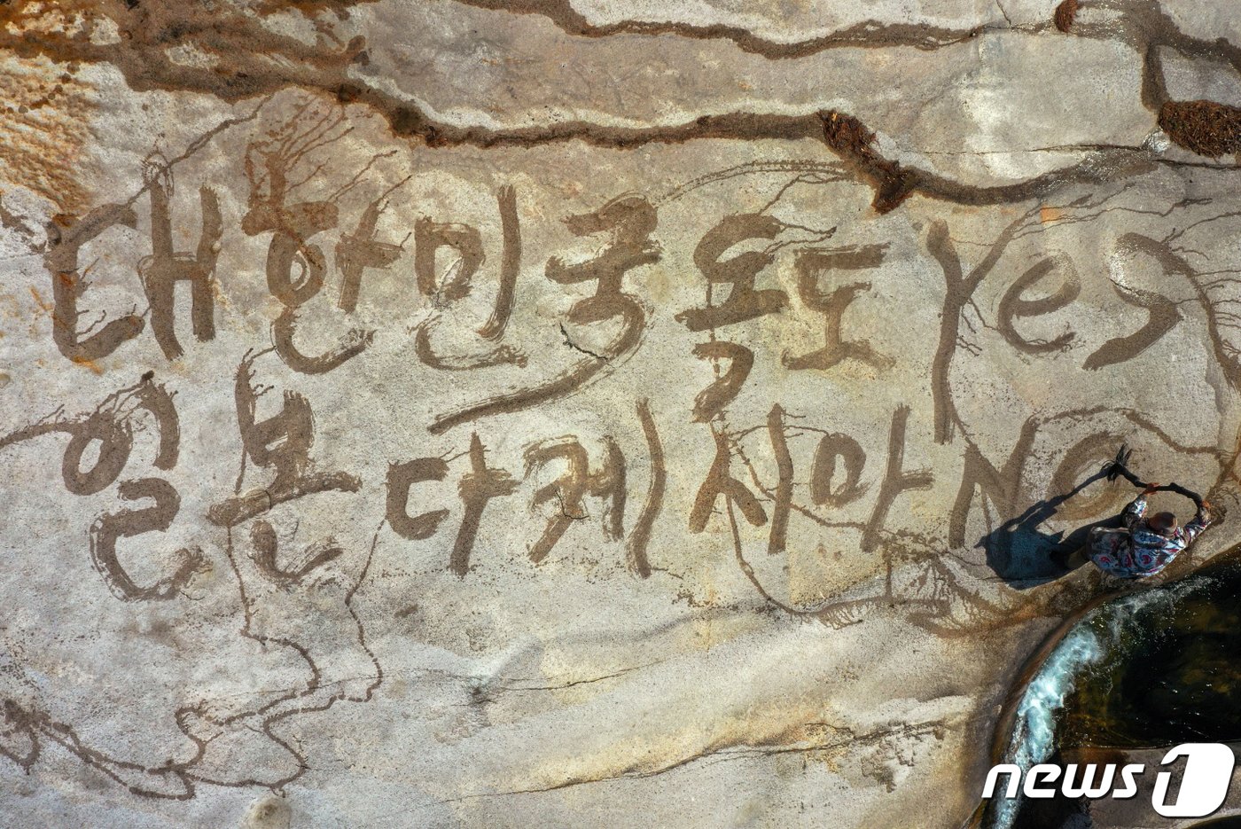 본문 이미지 - 서예가 김동욱 씨가 20일 울산 울주군 작천정 앞 바위에 물로 일본의 독도 망언과 역사 왜곡을 규탄하는 문구를 쓰고 있다. 김 서예가는 바위 위에 '대한민국 독도 Yes, 일본 다케시마 No'라고 적었다. 김 서예가는 "다케시마는 존재하지 않는다. 독도 만이 지구상에 존재하는 엄연한 대한민국의 영토＂라며 ＂일본은 썩은 역사를 하루 빨리 참회하고 사죄하라＂고 촉구했다. (김동욱 서예가 제공) 2023.2.20/뉴스1