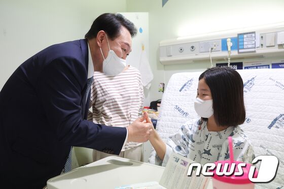 윤석열 대통령이 22일 서울 종로구 서울대 어린이병원 소아외과 병실을 방문해 환아와 손가락을 걸고 대화하고 있다. (대통령실 제공) (기사 내용과 무관한 자료 사진) 2023.2.22/뉴스1 © News1 오대일 기자