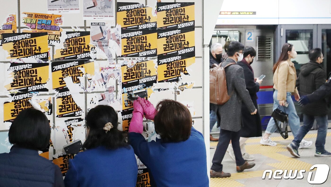본문 이미지 - 서울교통공사의 자회사 서울메트로환경 미화원들이 27일 오전 용산구 4호선 삼각지역 승강장에서 전국장애인차별철폐연대(전장연)의 출근길 시위 당시 부착한 선전용 스티커를 제거하고 있다. 2023.2.27/뉴스1 ⓒ News1 민경석 기자