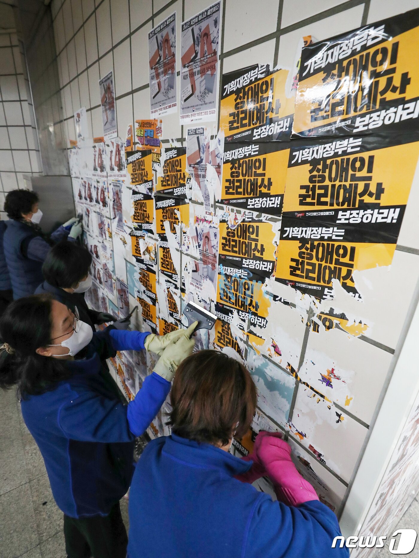 본문 이미지 - 서울교통공사의 자회사 서울메트로환경 미화원들이 27일 오전 용산구 4호선 삼각지역 승강장에서 전국장애인차별철폐연대(전장연)의 출근길 시위 당시 부착한 선전용 스티커를 제거하고 있다. 2023.2.27/뉴스1 ⓒ News1 민경석 기자