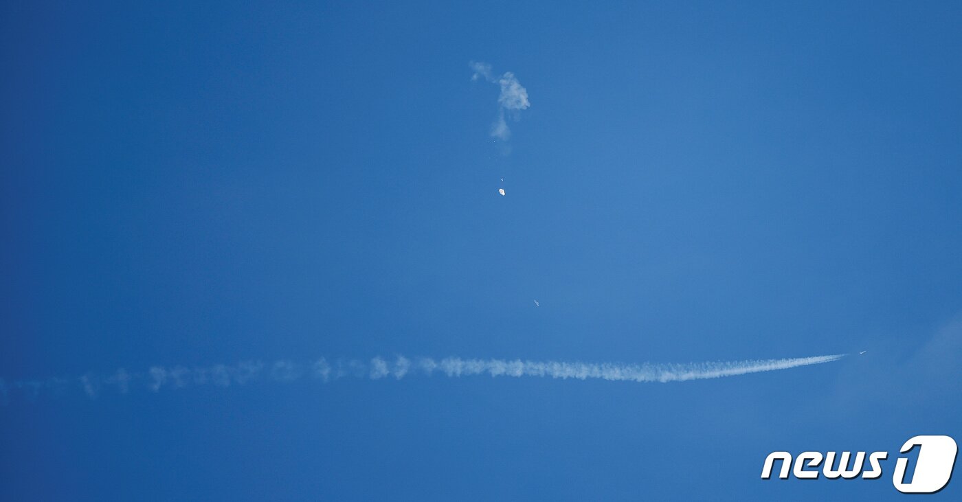 본문 이미지 - 4일(현지시간) 미국 사우스캐롤나이나주 서프사이드 해안에서 중국 정찰 풍선으로 추정되는 비행체가 떨어지는 모습. 아래 흰선은 정찰 풍선을 감시하기 위한 전투기의 궤적이다. ⓒ 로이터=뉴스1 ⓒ News1 박형기 기자
