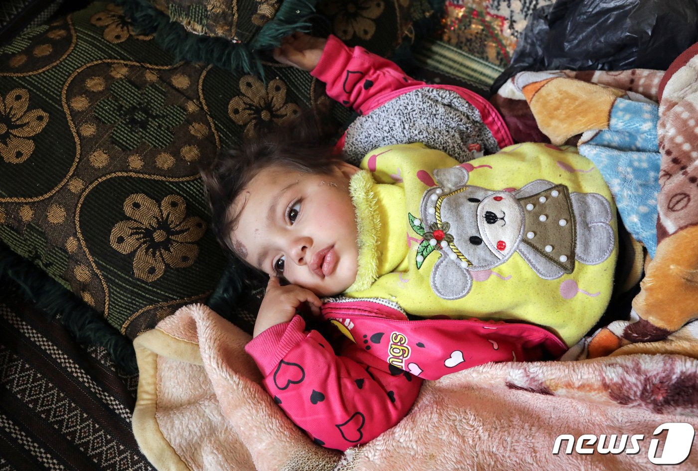 본문 이미지 - 8일(현지시간) 시리아 잔다리스 마을의 붕괴 현장에서 살아남은 압둘라만 알리 알마무드의 막내 딸. 아이와 아버지는 막대기와 담요로 얼기설기 만든 임시 대피소로 몸을 피했다. ⓒ 로이터=뉴스1 ⓒ News1 권진영 기자