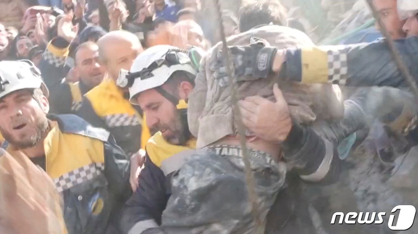 본문 이미지 - 8일(현지시간) 시리아 잔다리스에서 자원봉사자들이 지진 잔해 속에서 구조한 소년을 안고 안전한 곳으로 옮기고 있다. 골든타임 72시간이 지난 후에도 기적같은 구조가 이어지고 있다. ⓒ 로이터=뉴스1 ⓒ News1 권진영 기자