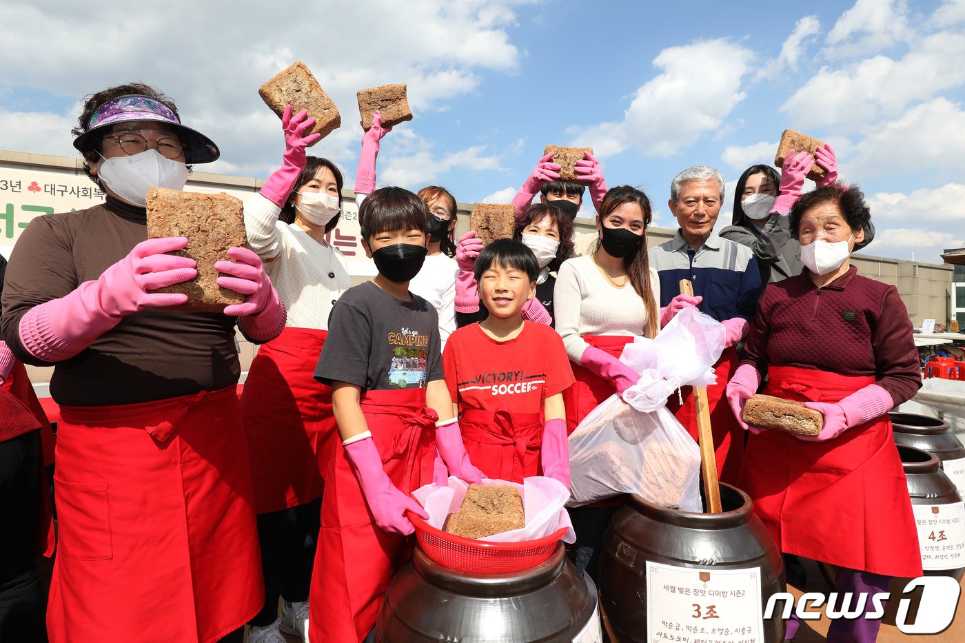 본문 이미지 - 15일 오후 대구 달서구노인종합복지관 옥상에서 열린 '달서구 온(溫)가족 장(醬) 담그는 날' 행사에 참여한 어르신과 어린이, 다문화가족 등 마을주민들이 장독대에 모여 장을 담그고 있다. 대구사회복지공동모금회 지원사업으로 마련된 이날 담근 장은 100일쯤 지나 어려운 이웃 1000여 가구와 나눌 예정이다. 2023.3.15/뉴스1 ⓒ News1 공정식 기자