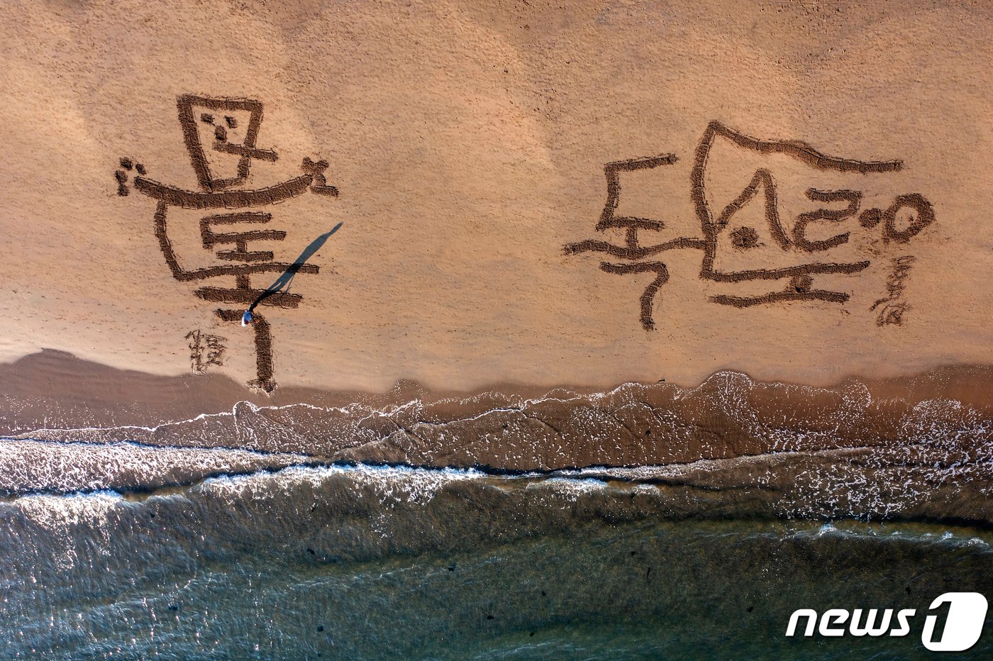 본문 이미지 - 서예가 김동욱 씨가 16일 오전 경북 포항시 북구 영일대해수욕장 백사장에서 독도가 우리 땅임을 알리는 퍼포먼스를 펼치고 있다. 이날 김 씨는 '우리 땅 독도'를 다양한 글꼴로 표현했다. (서예가 김동욱 씨 제공) 2023.3.16/뉴스1 ⓒ News1 최창호 기자