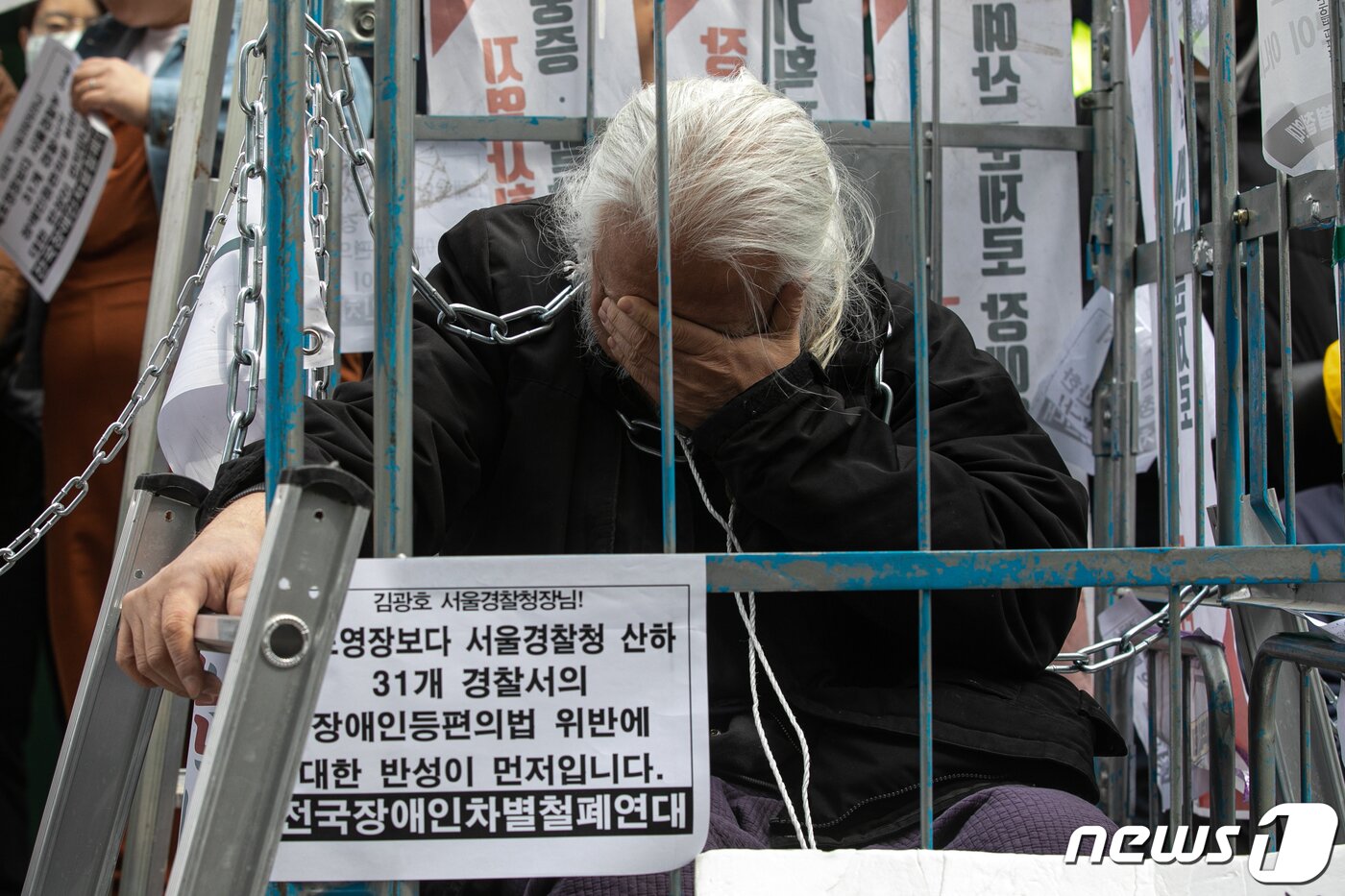 본문 이미지 - 박경석 전국장애인차별철폐연대(전장연) 대표가 17일 오전 서울 종로구 서울지방경찰청 앞에서 몸에 쇠사슬을 두르고 철창 속에서 법원의 체포영장 발부에 따른 입장발표 기자회견에 참석해 생각에 잠겨있다.  ⓒ News1 이승배 기자