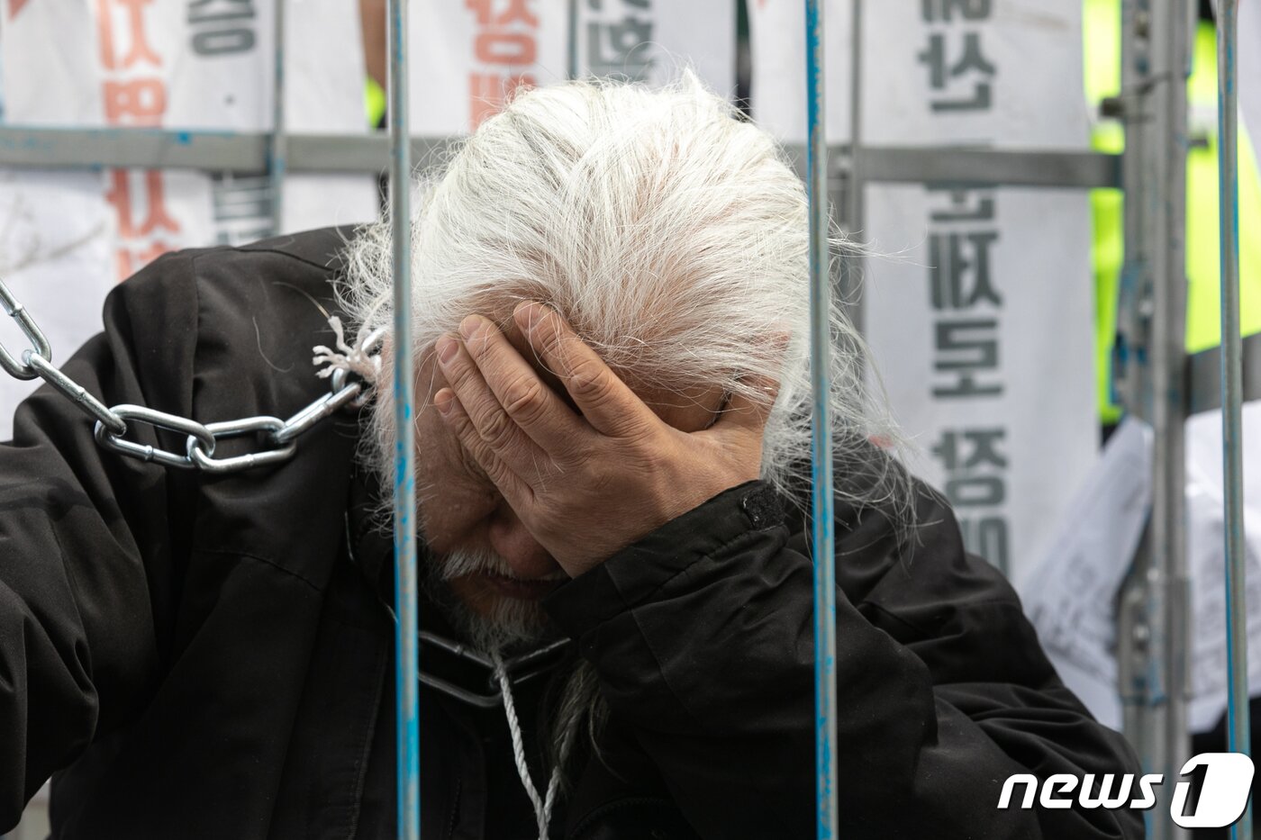 본문 이미지 - 박경석 전국장애인차별철폐연대(전장연) 대표가 17일 오전 서울 종로구 서울지방경찰청 앞에서 몸에 쇠사슬을 두르고 철창 속에서 법원의 체포영장 발부에 따른 입장발표 기자회견에 참석해 생각에 잠겨있다. 2023.3.17/뉴스1 ⓒ News1 이승배 기자