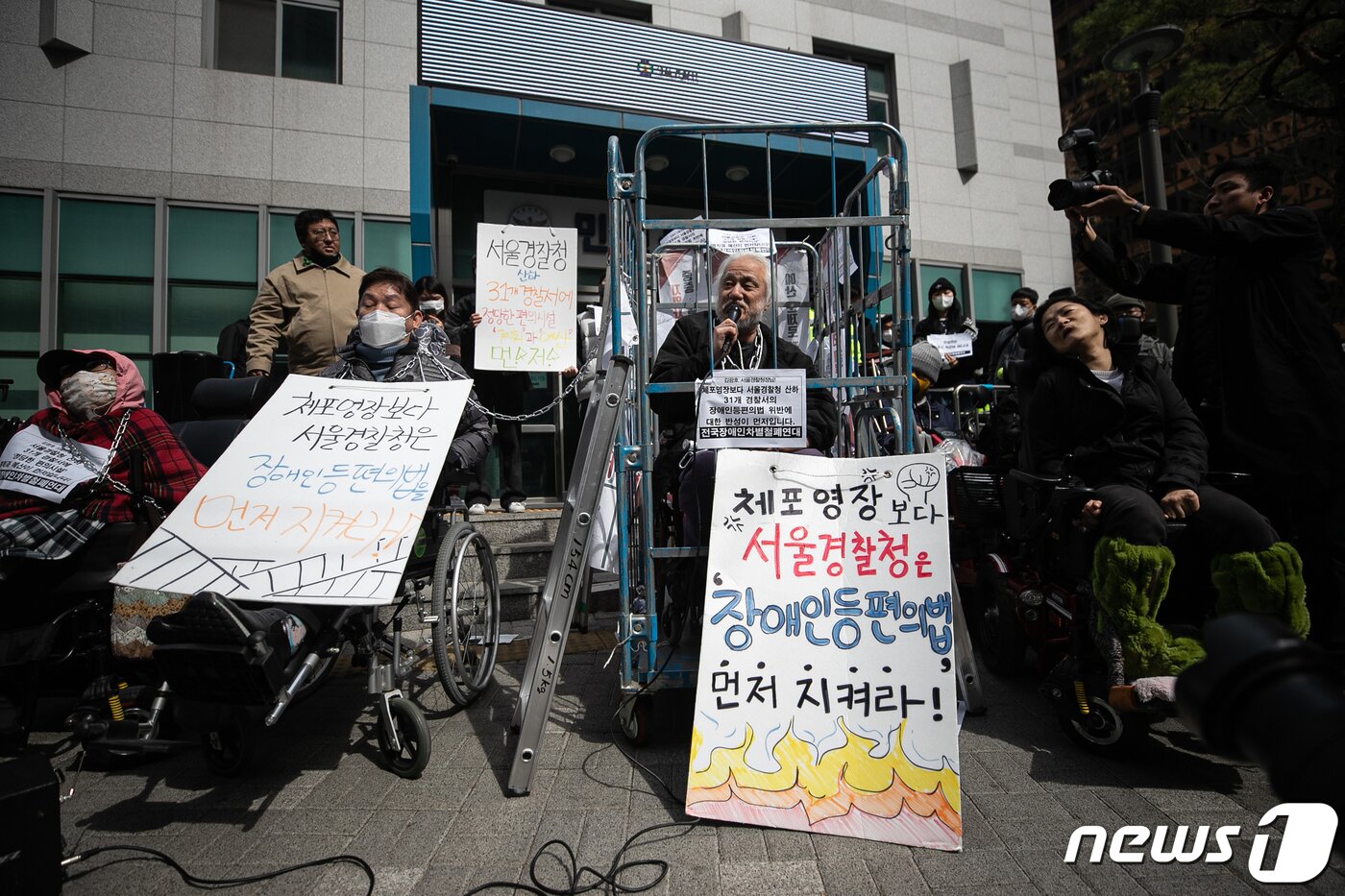 본문 이미지 - 박경석 전국장애인차별철폐연대(전장연) 대표가 17일 오전 서울 종로구 서울지방경찰청 앞에서 몸에 쇠사슬을 두르고 철창 속에서 법원의 체포영장 발부에 따른 입장발표 기자회견을 하고 있다.  2023.3.17/뉴스1 ⓒ News1 이승배 기자