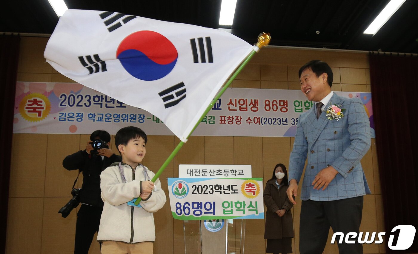 본문 이미지 - 2일 오전 대전 서구 둔산초등학교에서 열린 입학식에서 박종용 교장이 신입생 대표에게 태극기를 전달하고 있다. 둔산초는 매년 입학생 전원에게 태극기를 선물한다. 2023.3.2/뉴스1 ⓒ News1 김기태 기자