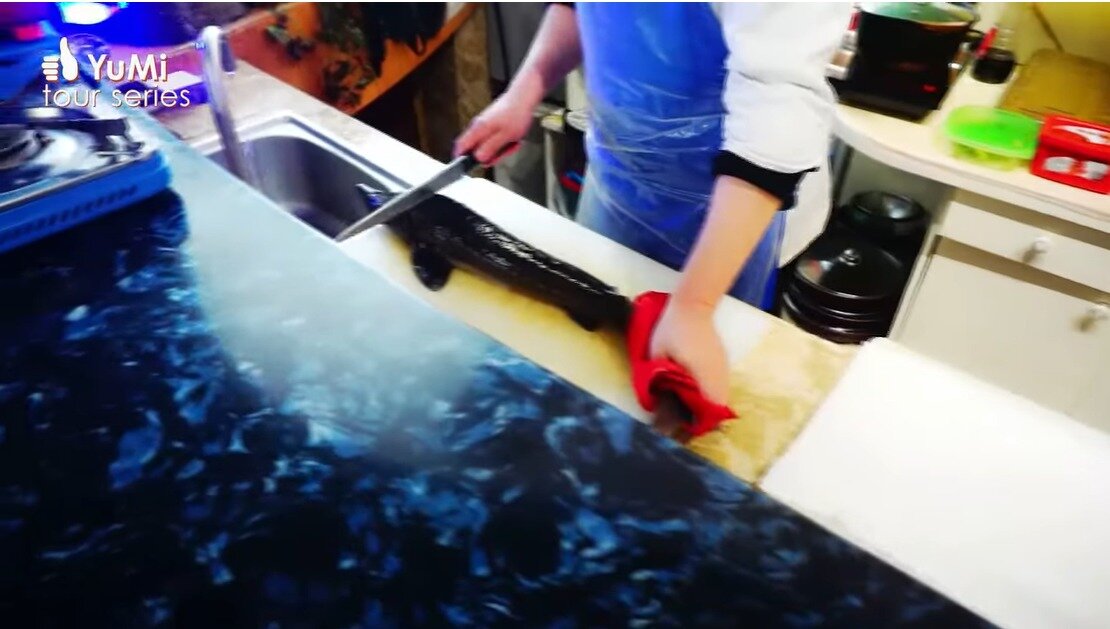 본문 이미지 -   북한 유튜버 유미가 공개한 대동강수산물식당 모습. 요리사가 철갑상어를 손질하고 있다. (출처=유튜브 Olivia Natasha- YuMi Space DPRK daily)