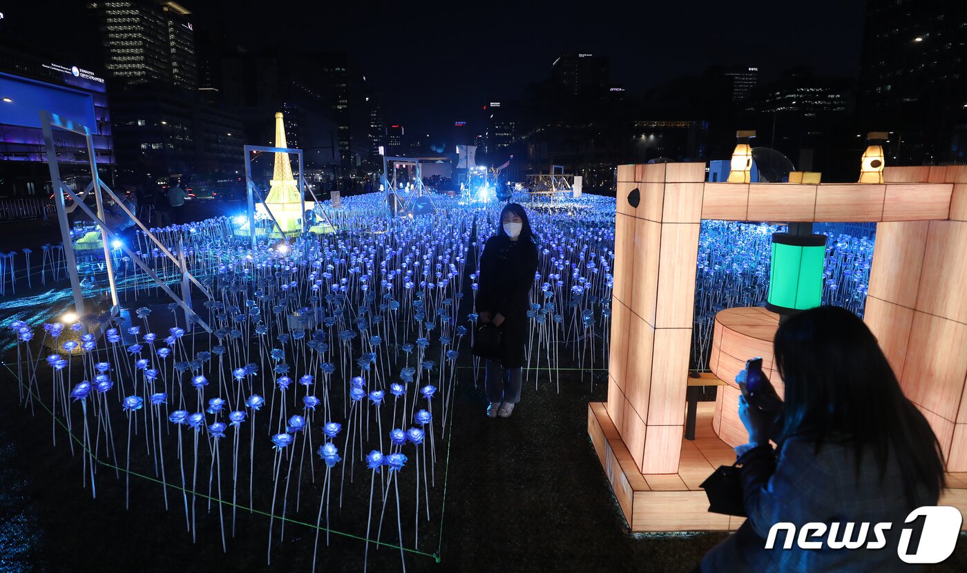 본문 이미지 - 30일 오후 서울 종로구 광화문광장에서 열린 '광화에서 빛; 나이다'를 찾은 시민들이 불 밝힌 LED 장미를 배경으로 사진을 찍고 있다. 2023.3.30/뉴스1 ⓒ News1 김진환 기자