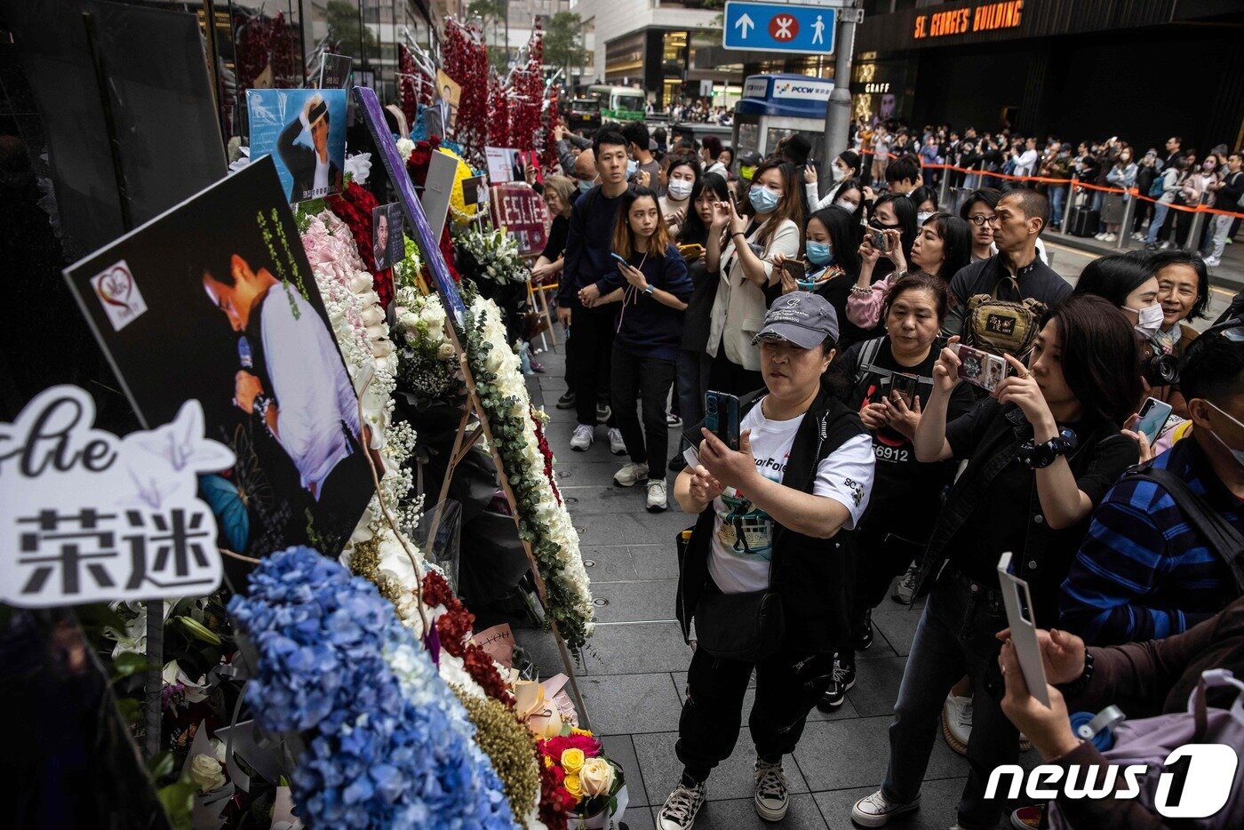 본문 이미지 - 홍콩의 가수 겸 배우였던 장국영 사망 20주기를 맞은 1일(현지시간) 홍콩에서 시민들이 길가에 놓인 추모 화환을 카메라에 담고 있다. 2023.04.01. ⓒ AFP=뉴스1 ⓒ News1 김성식 기자