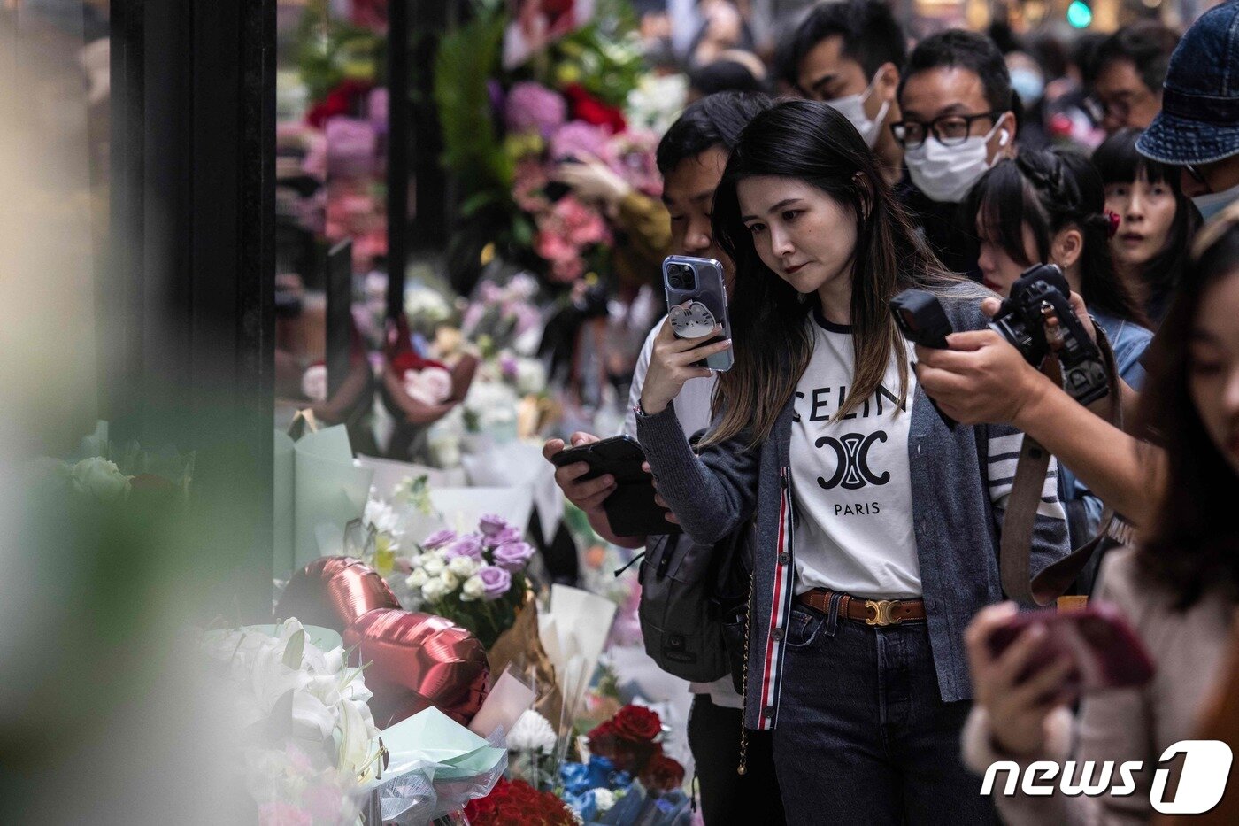 본문 이미지 - 홍콩의 가수 겸 배우였던 장국영의 사망 20주기를 맞은 1일(현지시간) 홍콩에서 시민들이 길가에 놓인 추모 화환과 그의 생전 모습을 카메라에 담고 있다. 2023.04.01. ⓒ AFP=뉴스1 ⓒ News1 김성식 기자