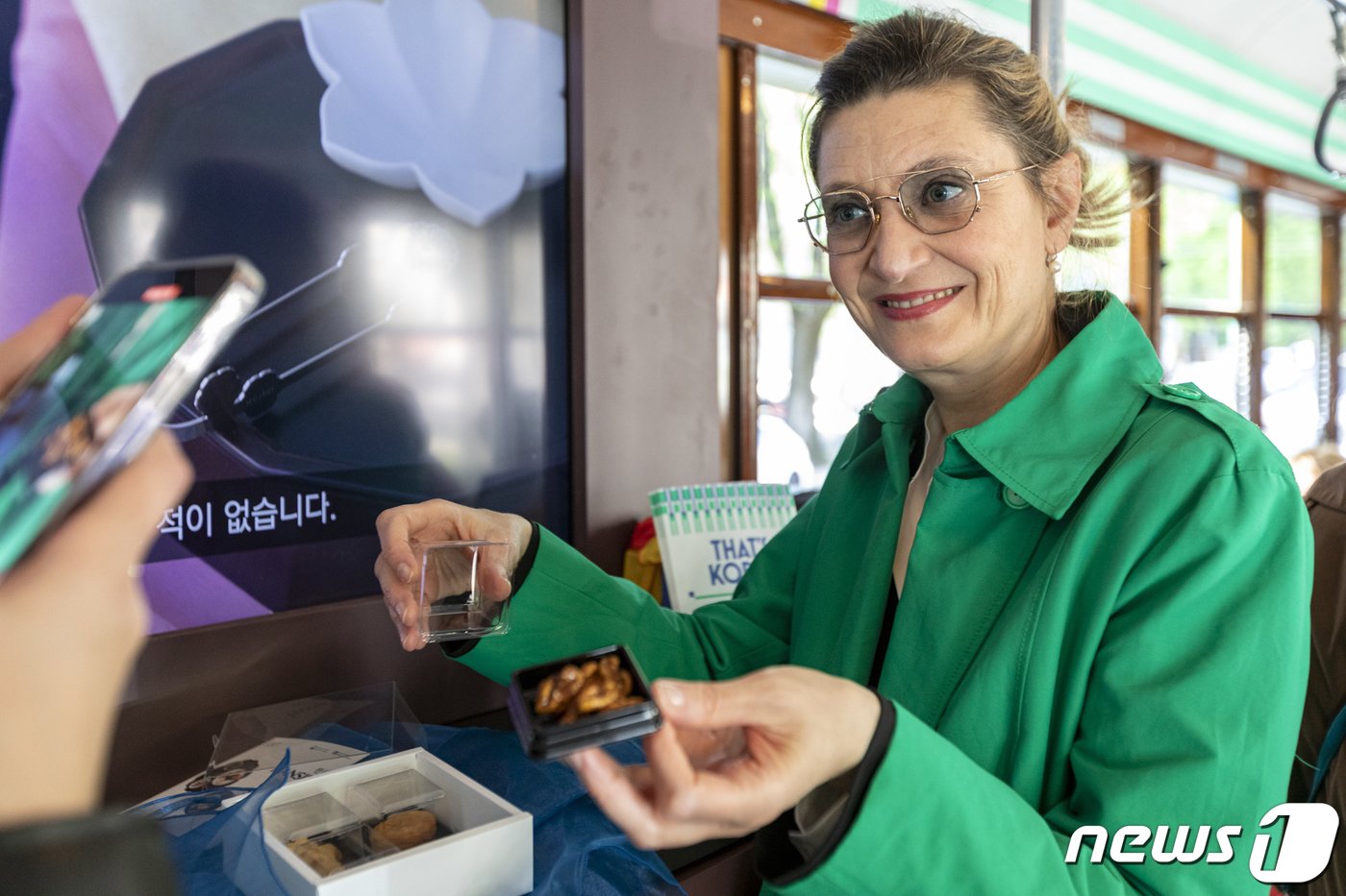 본문 이미지 - 외국인이 한식문화 홍보 트램에서 제공한 전통다과를 들고 기념촬영을 하고 있다. (사진은 기사 내용과 무관) (한국공예디자인문화진흥원 제공)/뉴스1