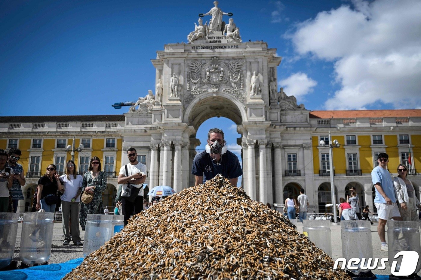 본문 이미지 - 독일의 환경운동가 안드레아스 노에가 방독면을 쓴 채 65만개의 담배꽁초 뒤에 서서 촬영하고 있다. ⓒ AFP=뉴스1 ⓒ News1 박형기 기자