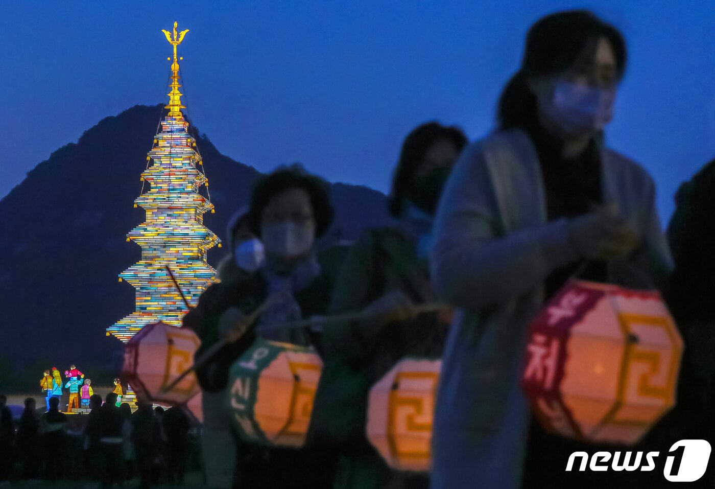 본문 이미지 - 26일 오후 서울 종로구 광화문광장에서 열린 '2023 부처님오신날 봉축점등식'에서 참석자들이 철물 구조와 한지 공예로 만든 20m 높이의 수마노탑 주변 탑돌이를 하고 있다. 2023.4.26/뉴스1 ⓒ News1 민경석 기자